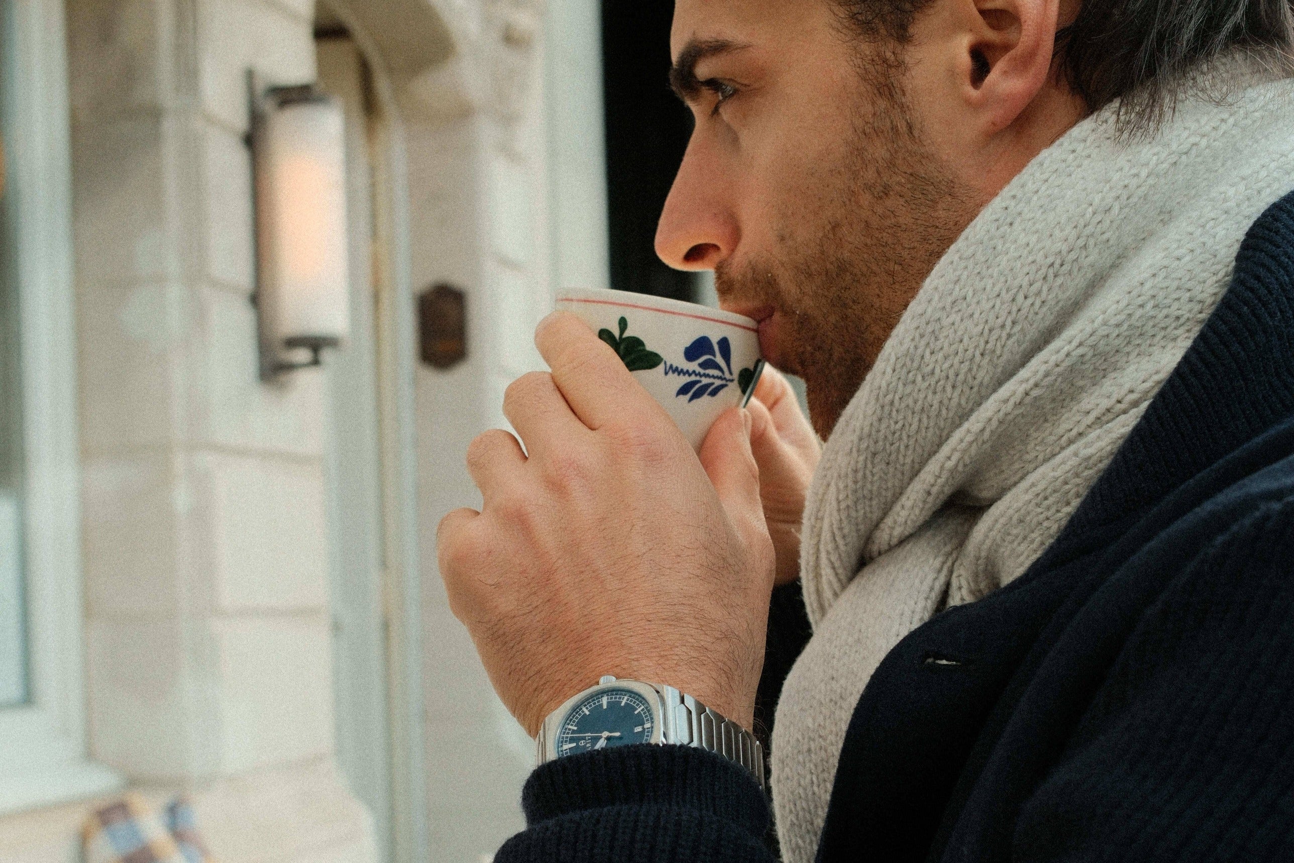 Man drinking from a cup in an outdoor cafe setting